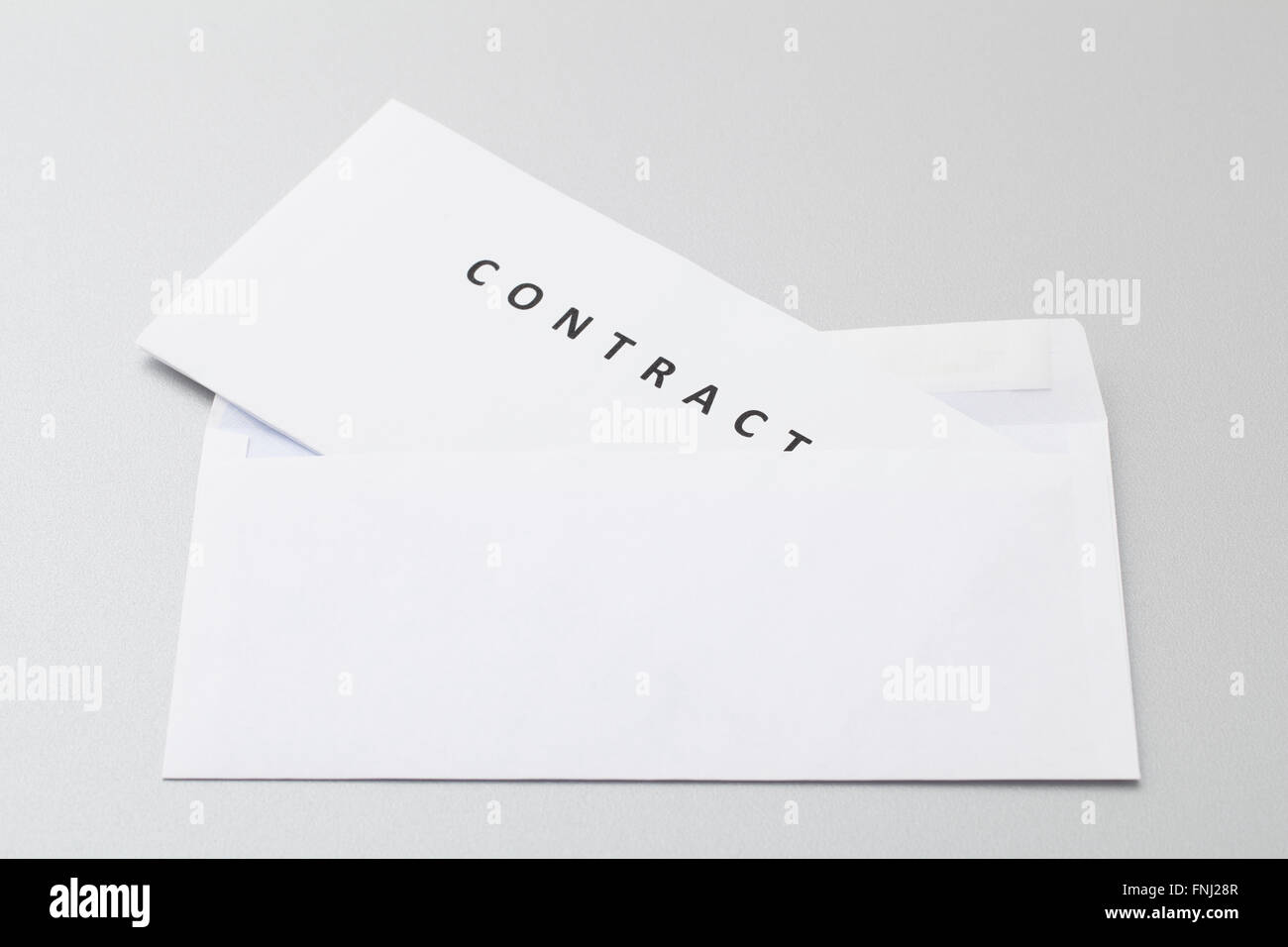 Folded white sheets with contract put in blank white envelope, ready for sending by post isolated on background. Stock Photo