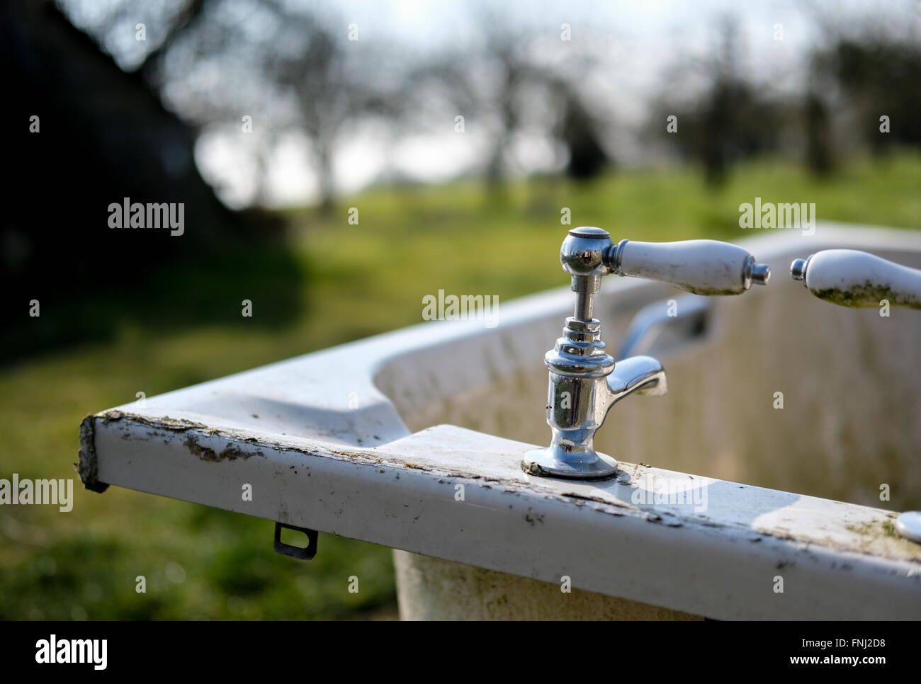 Old, abandoned ceramic bath and chrome water taps as seen in a field