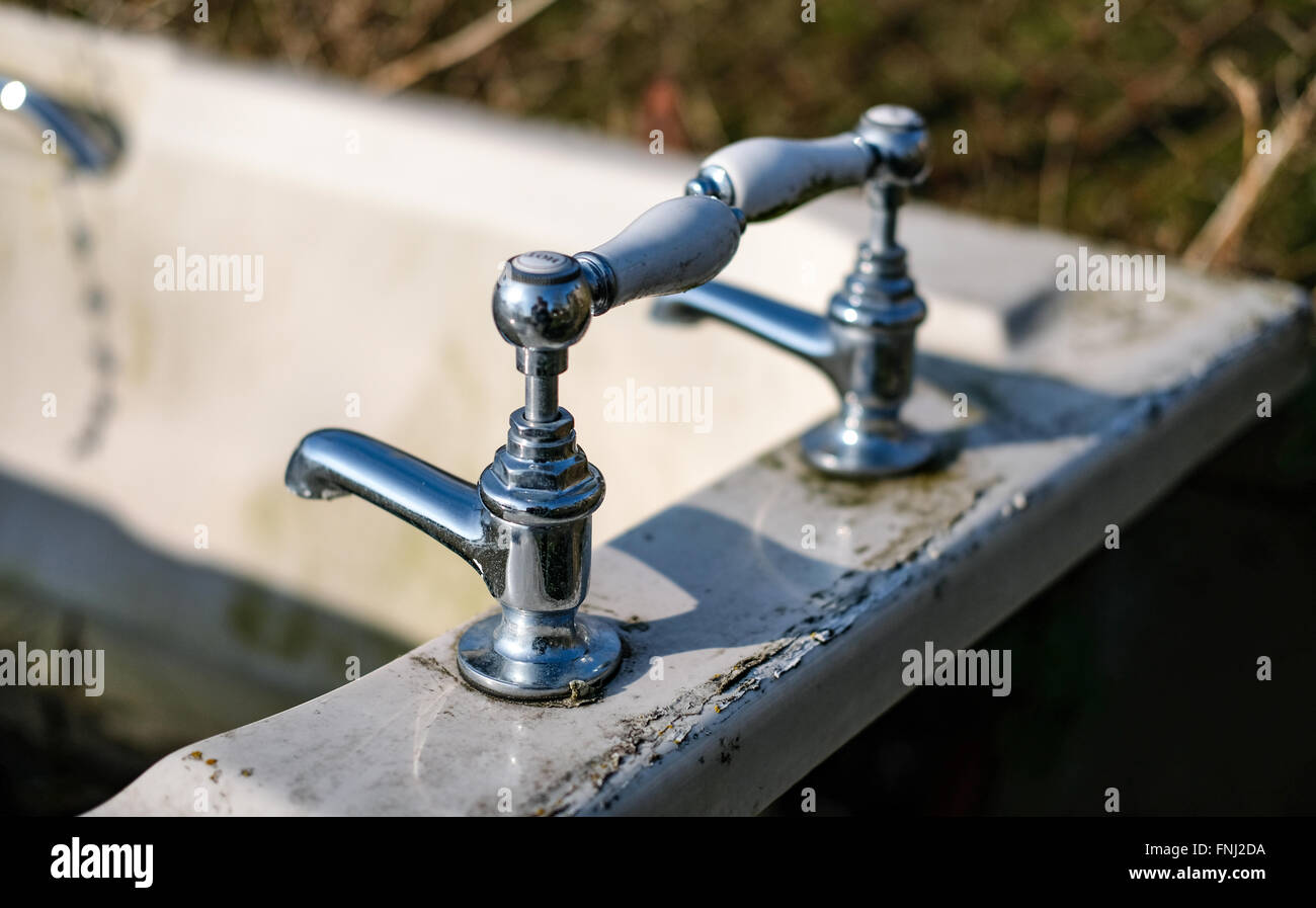 Old, abandoned ceramic bath and chrome water taps as seen in a field