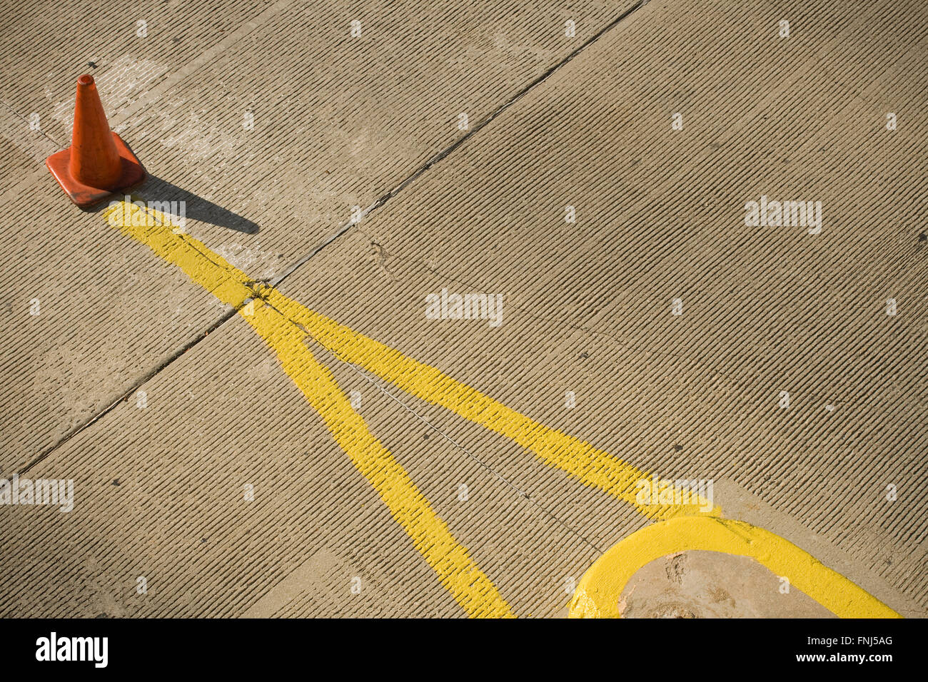 Orange traffic cone and yellow lines in parking lot Stock Photo
