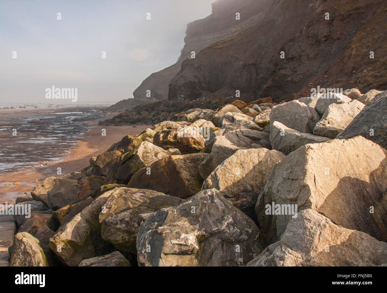 A foggy day in Whitby in North Yorkshire showing the rocky beach and cliffs Stock Photo