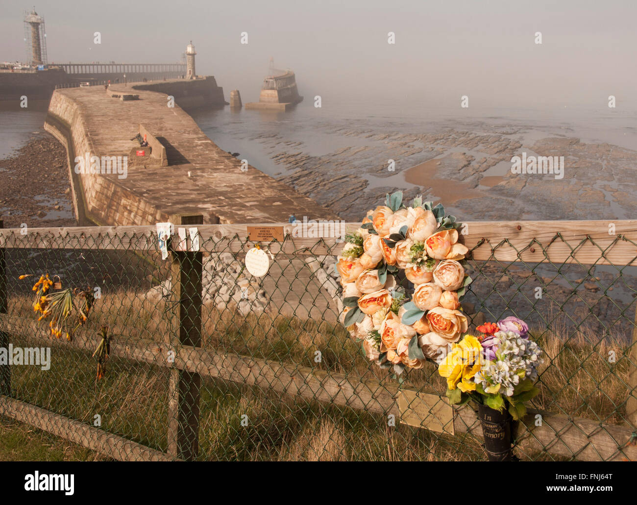 A foggy day in Whitby in North Yorkshire showing pier,harbour and flowers Stock Photo