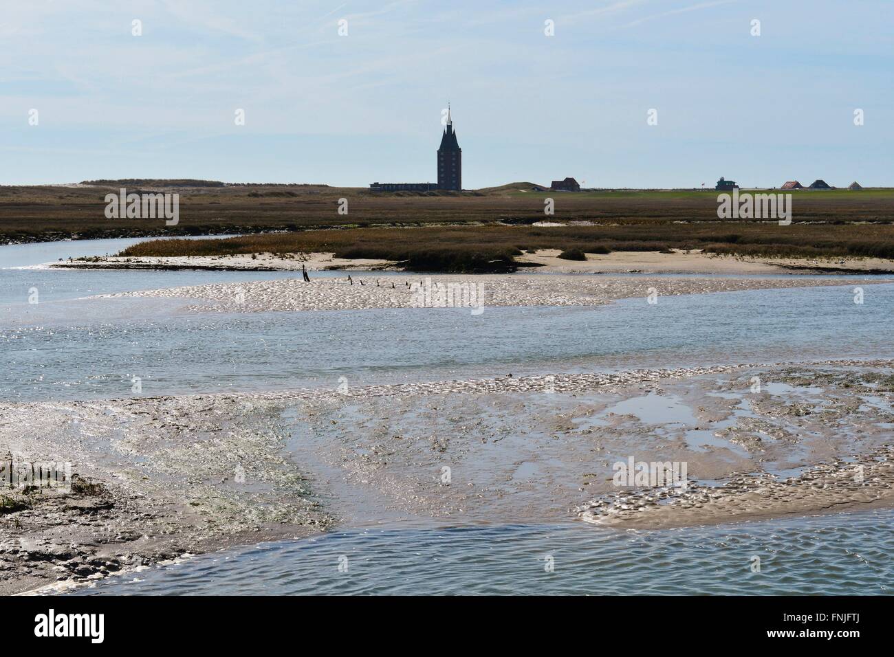 The prominent silhouette of Wangerooge's tower Westturm behind the wadden area and the wet meadows, 20 April 3015 Stock Photo