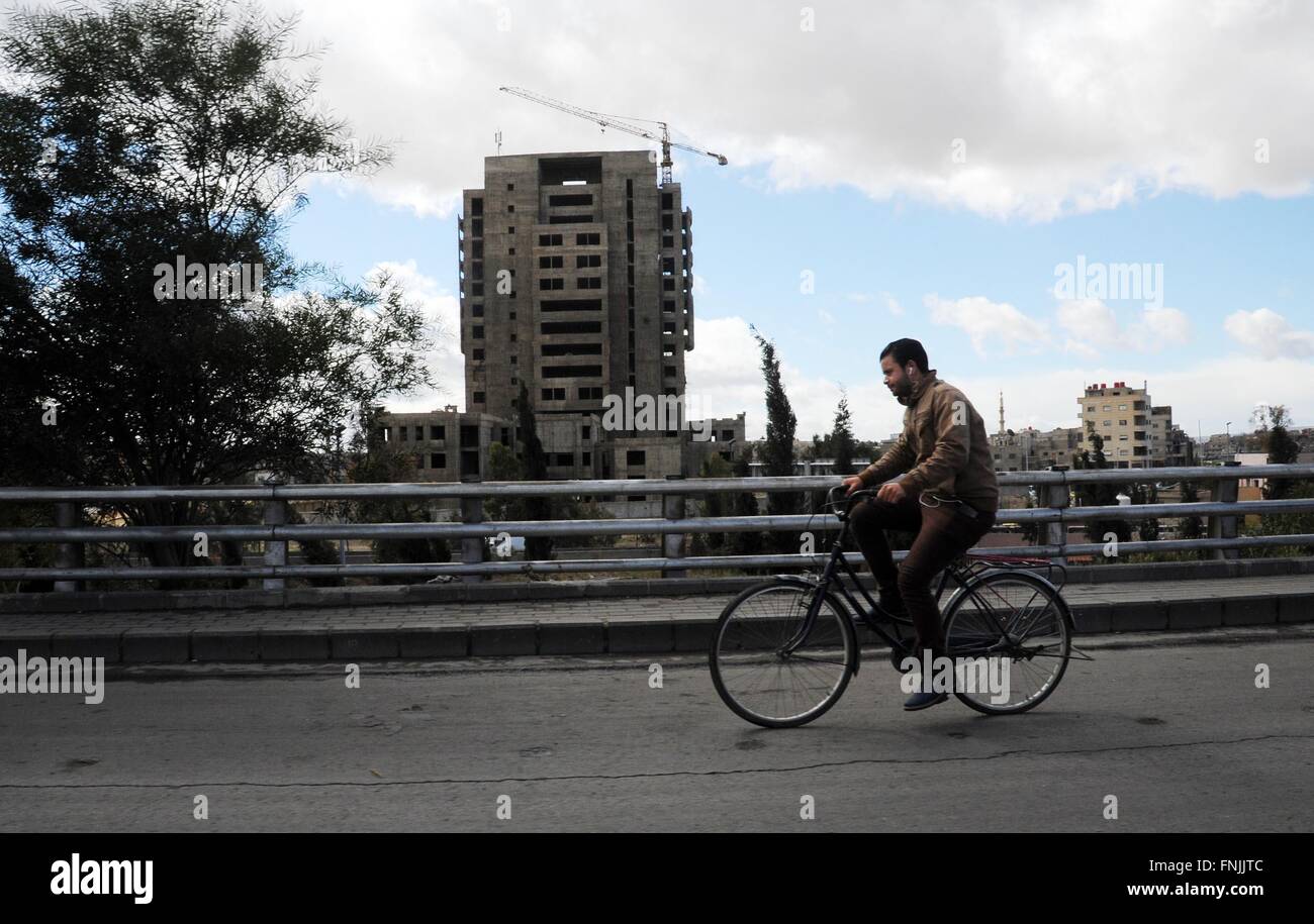 Damascus, Syria. 15th Mar, 2016. A Syrian man rides a bicycle on a street in Damascus, capital of Syria, on March 15, 2016. Tuesday marks the 5th anniversary of the Syrian civil war, which broke out in March 2011, claiming the lives of over 250,000 people and displacing half of the country's 23 million population. © Ammar/Xinhua/Alamy Live News Stock Photo