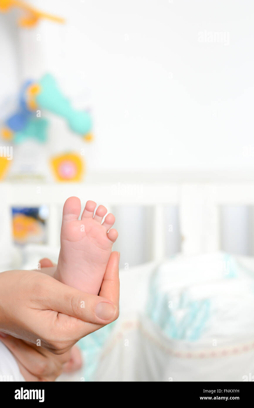 Young mother holding newborn baby foot in her palms Stock Photo