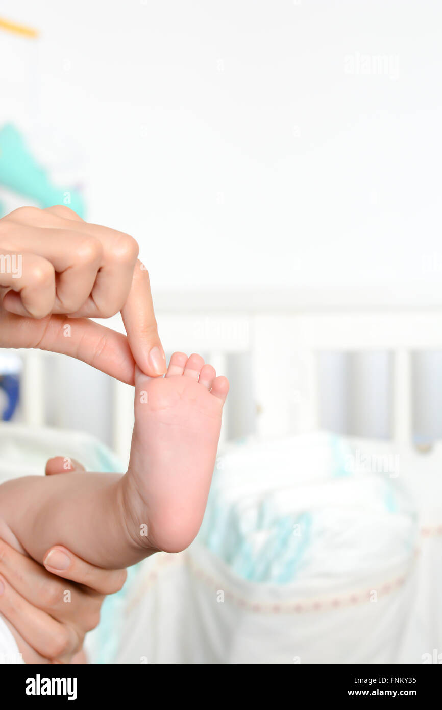 Young mother holding newborn baby foot in her palms Stock Photo