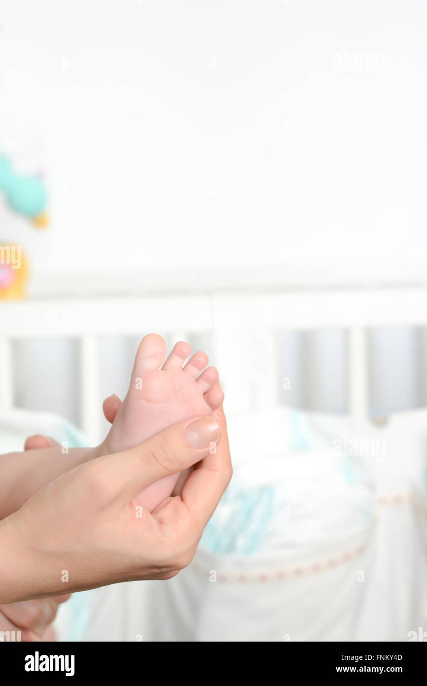 Young mother holding newborn baby foot in her palms Stock Photo