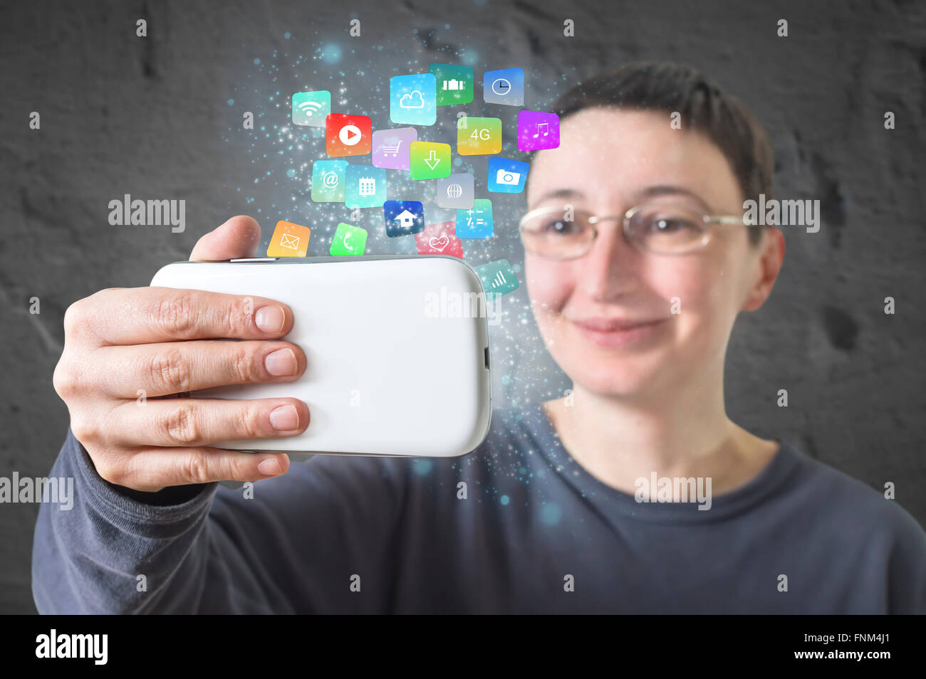 Woman holding a smart phone with modern colorful floating apps and icons. Selective focus. Stock Photo