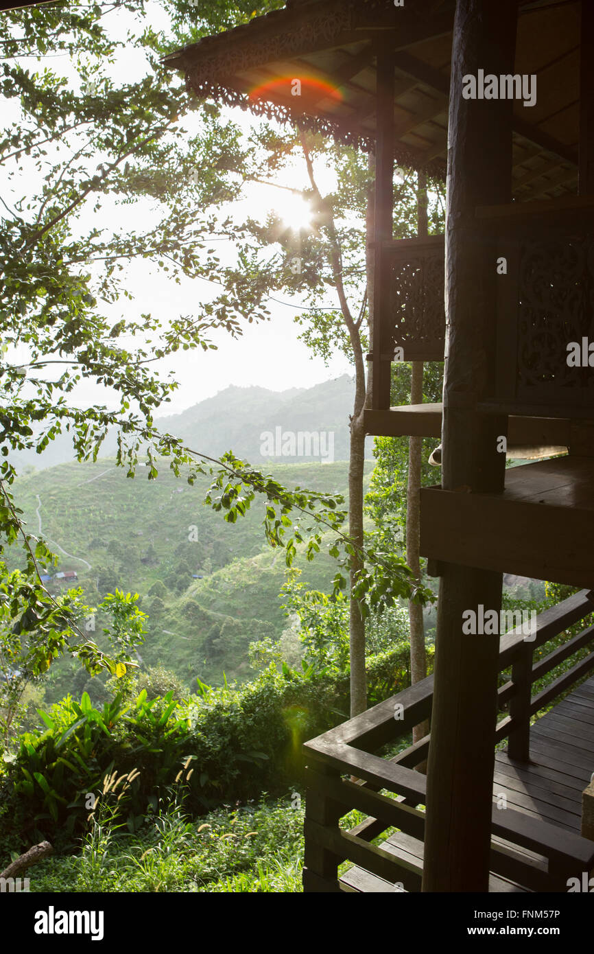 Morning sun flare at wooden bungalow at eco-resort in Penang, Malaysia with views of forest and mountain Stock Photo