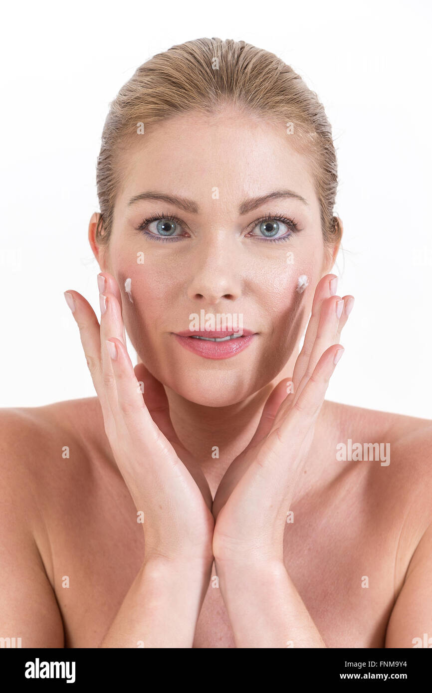 Smiling young woman applying face cream Stock Photo Alamy