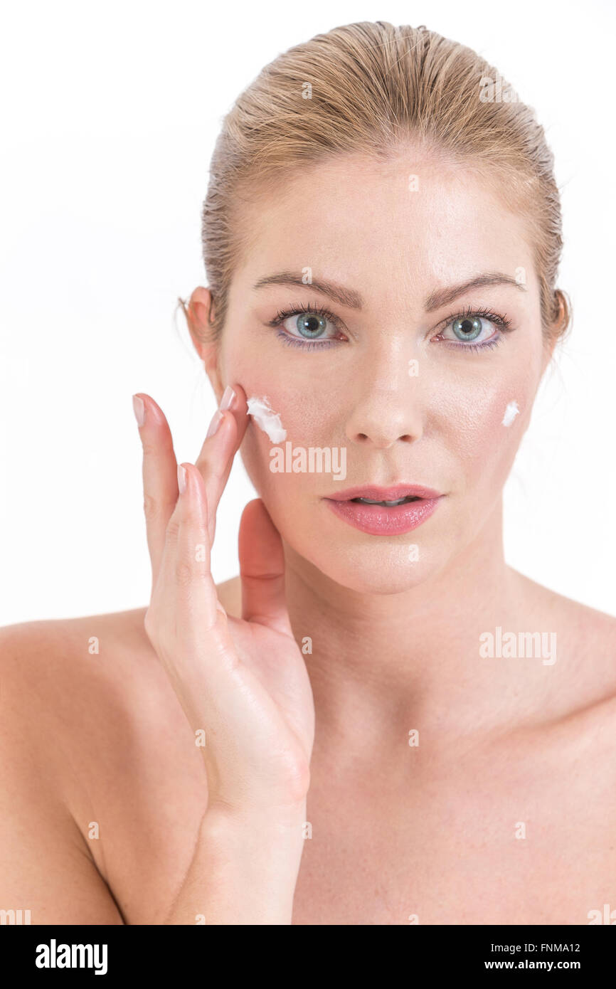 Smiling young woman applying face cream. Stock Photo