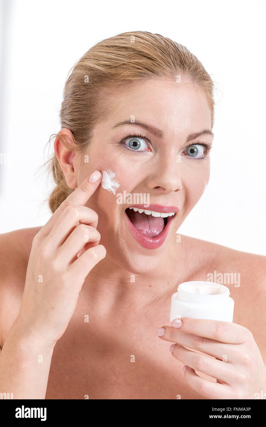 Smiling young woman applying face cream Stock Photo Alamy