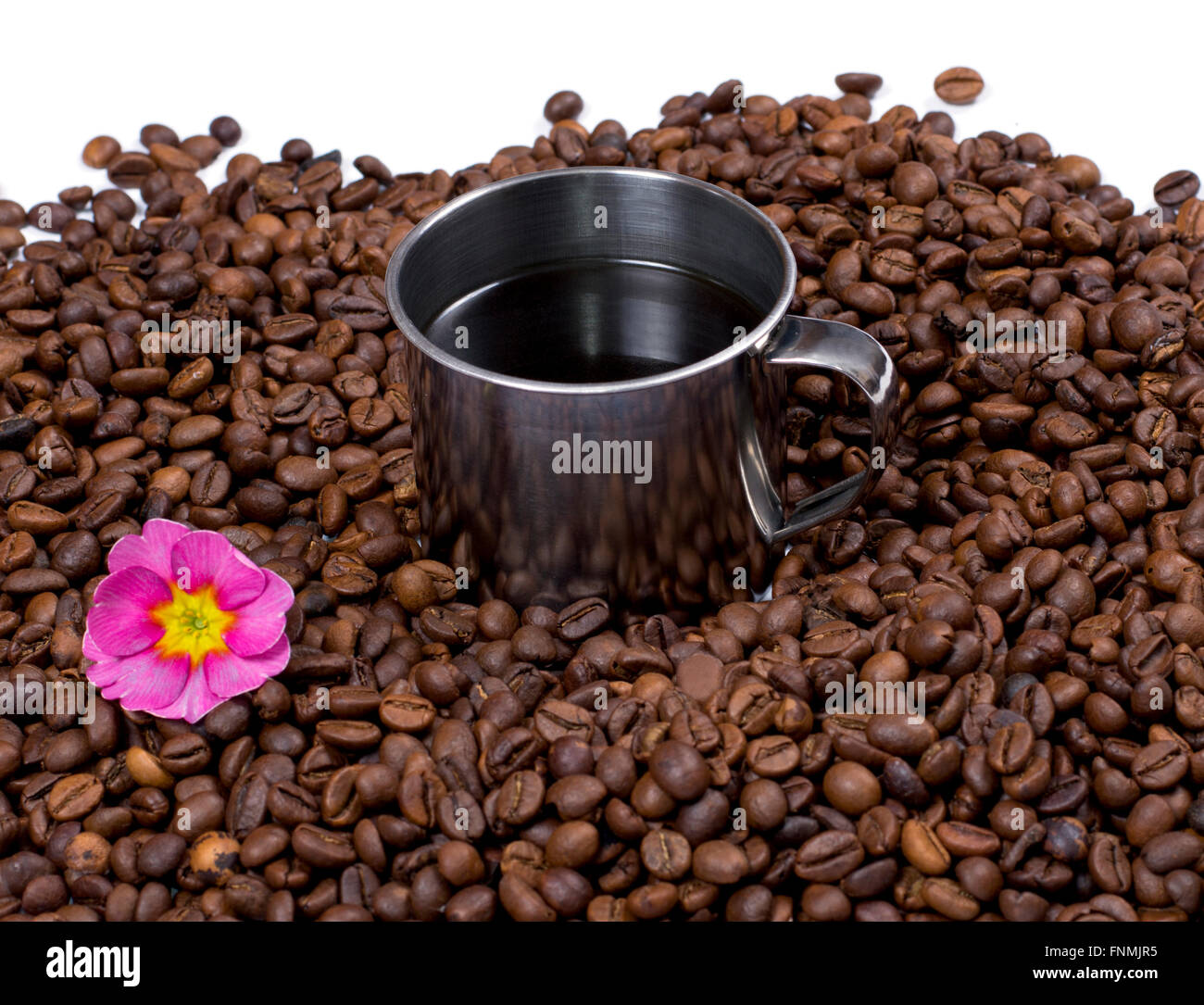 flower and steel cup of coffee in coffee grains Stock Photo