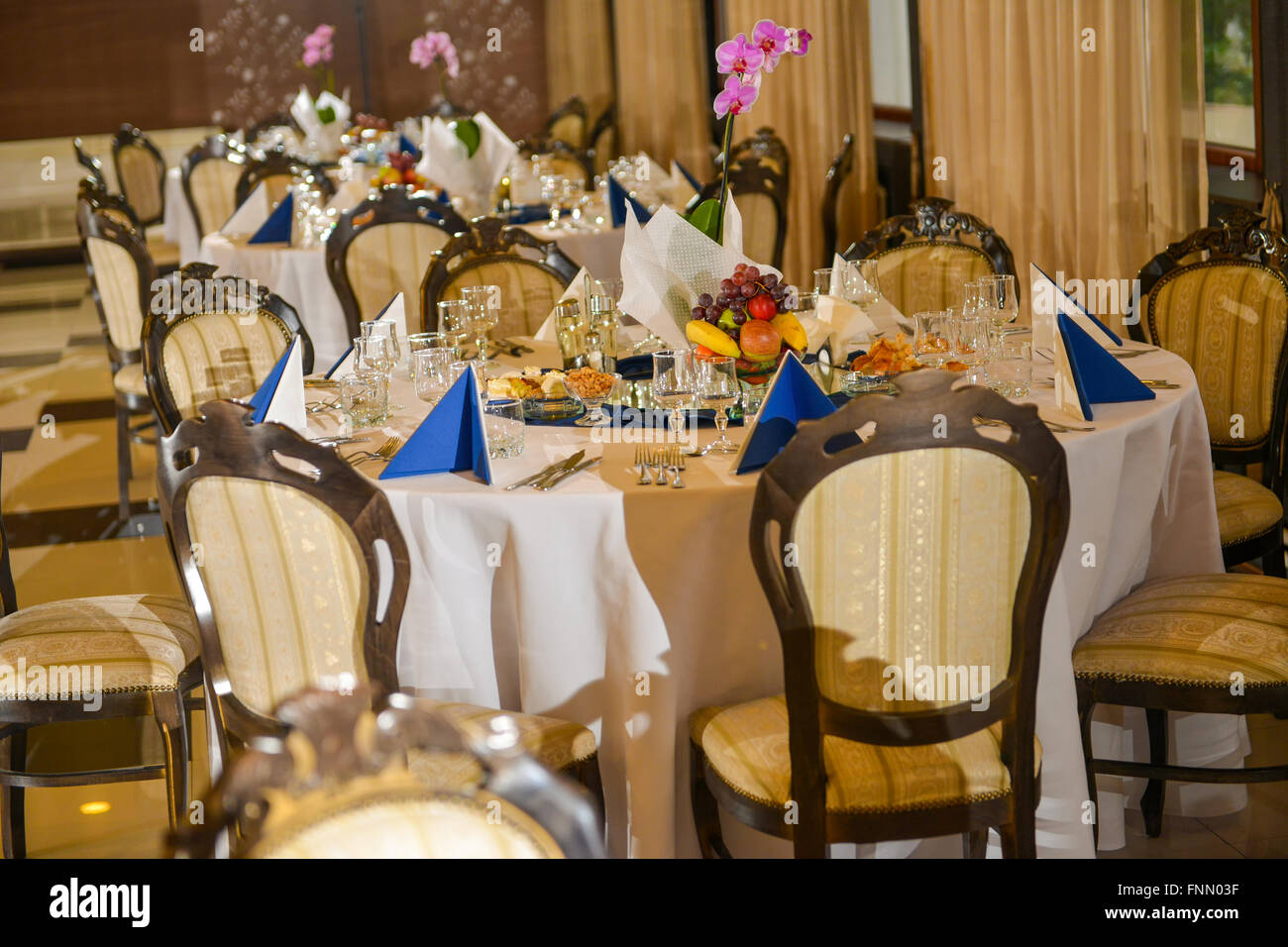 Row of tables arranged to receive clients Stock Photo