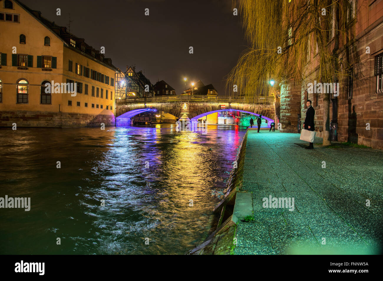 Scenic view View on river in Strasbourg, France at night. Romantic lights reflecting on the water and traditional houses and bui Stock Photo