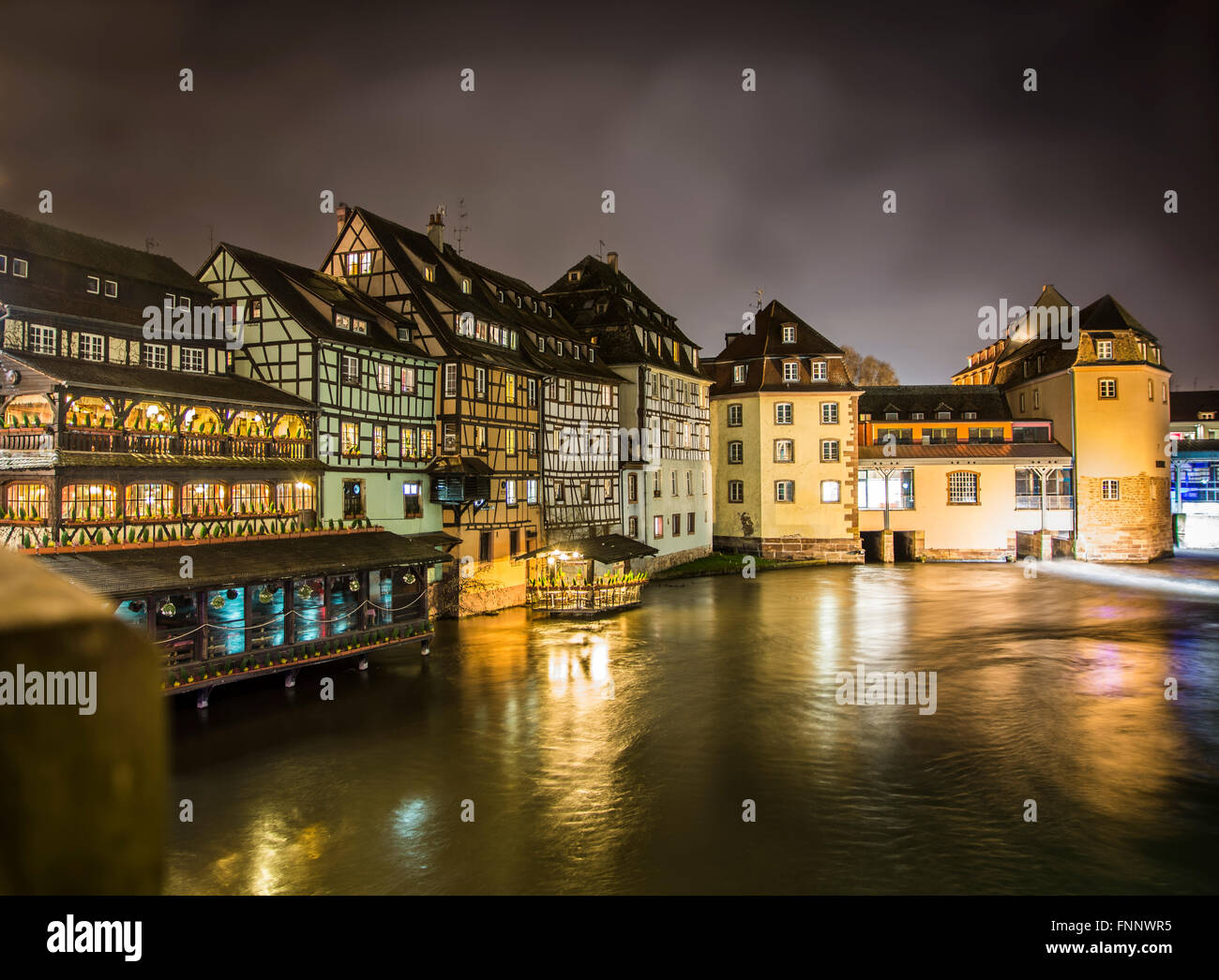 Scenic view View on river in Strasbourg, France at night. Romantic lights reflecting on the water and traditional houses and bui Stock Photo