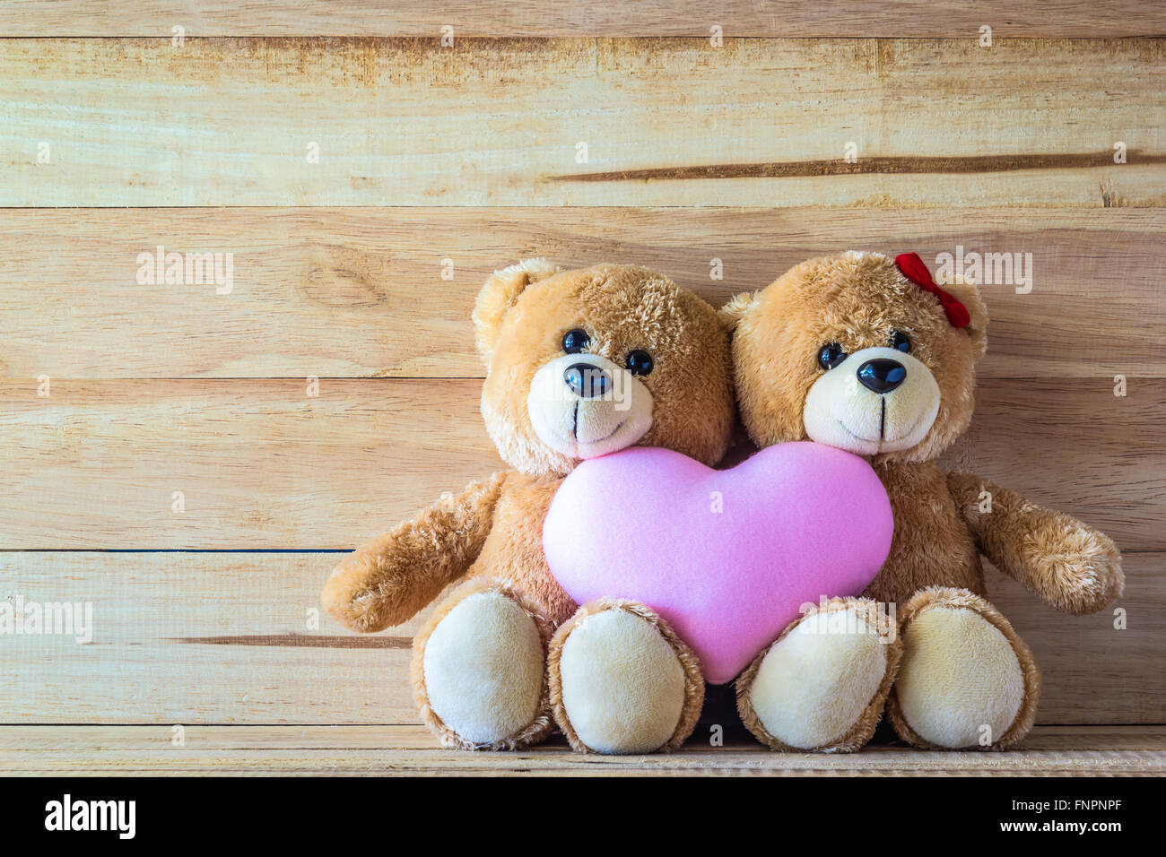 Couple teddy bear with Pink heart-shaped pillow on plank wood board, Valentine concept Stock Photo