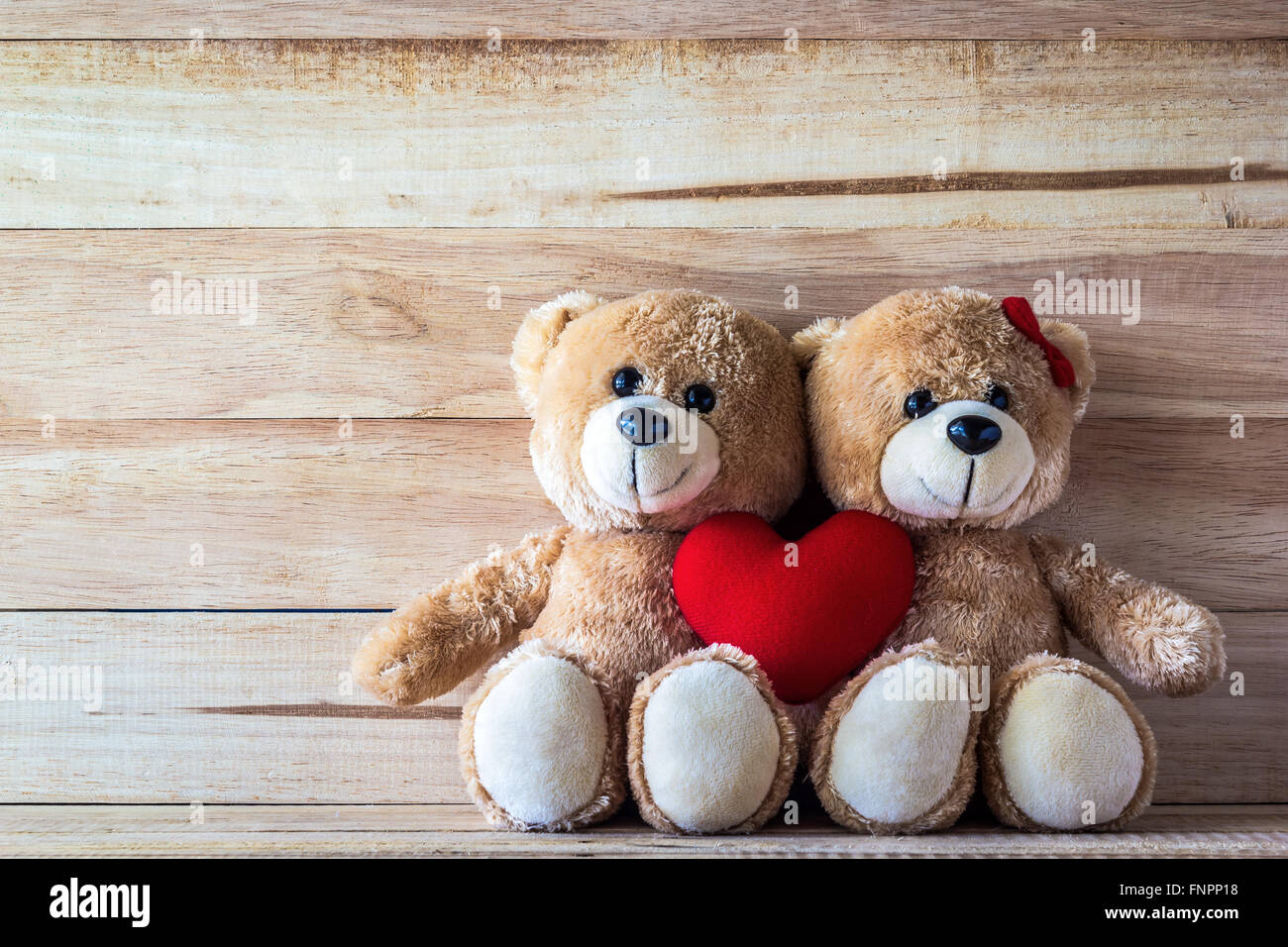 Couple teddy bear with Pink heart-shaped pillow on plank wood board, Valentine concept Stock Photo