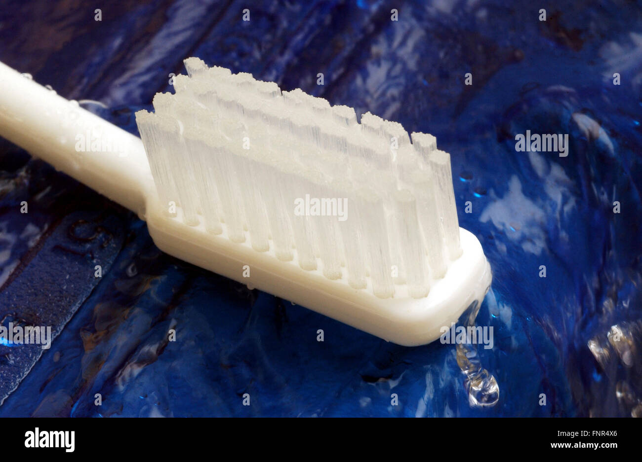 A white toothbrush lying in a pool of water. Stock Photo
