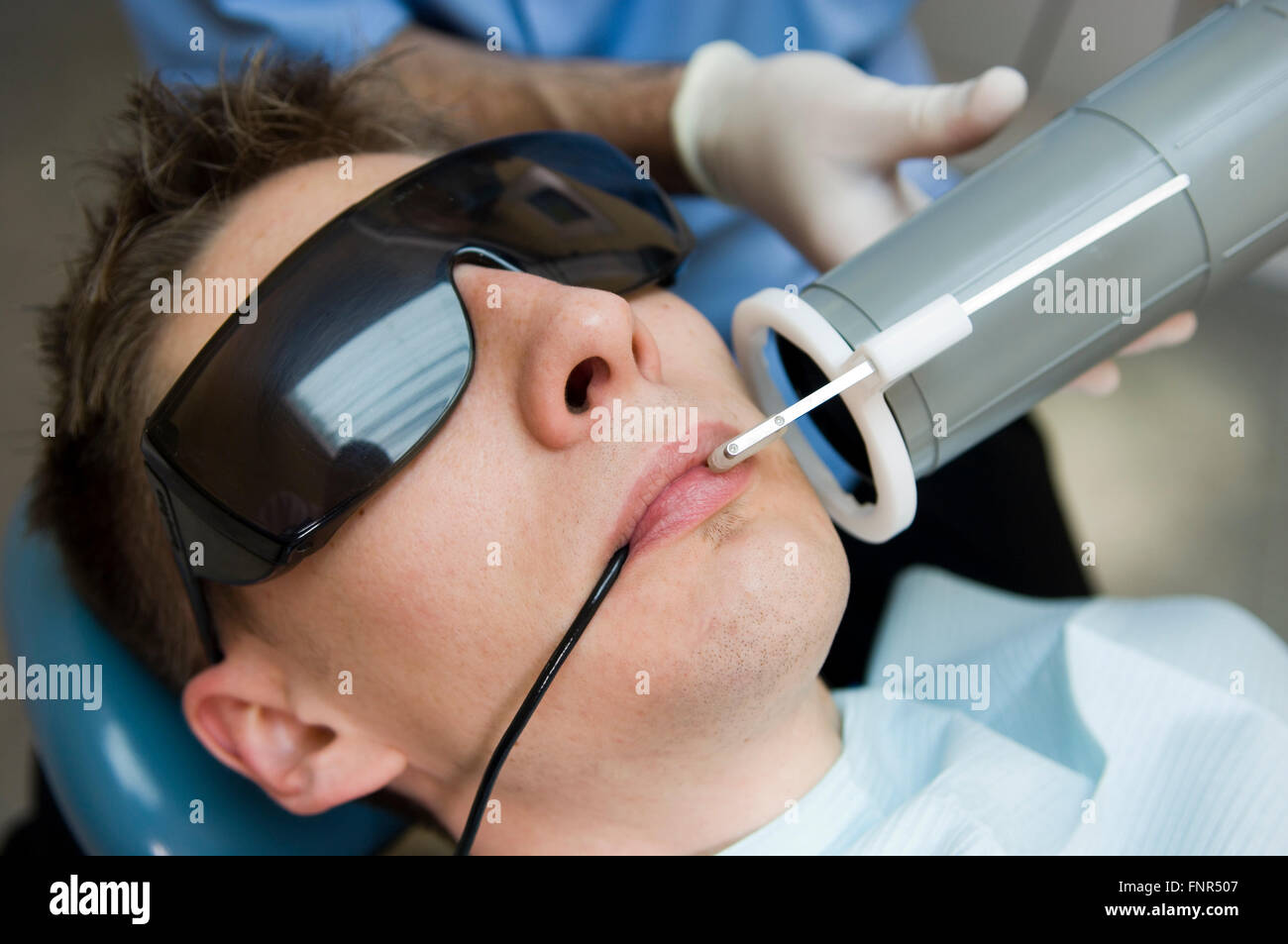 Dentist wearing safety glasses and mouth mask prepares to xray the