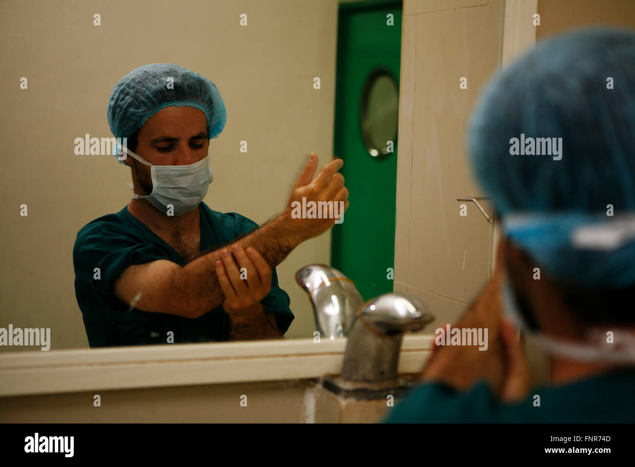 A surgeon thoroughly washing his hands and arms prior to performing surgery. Stock Photo