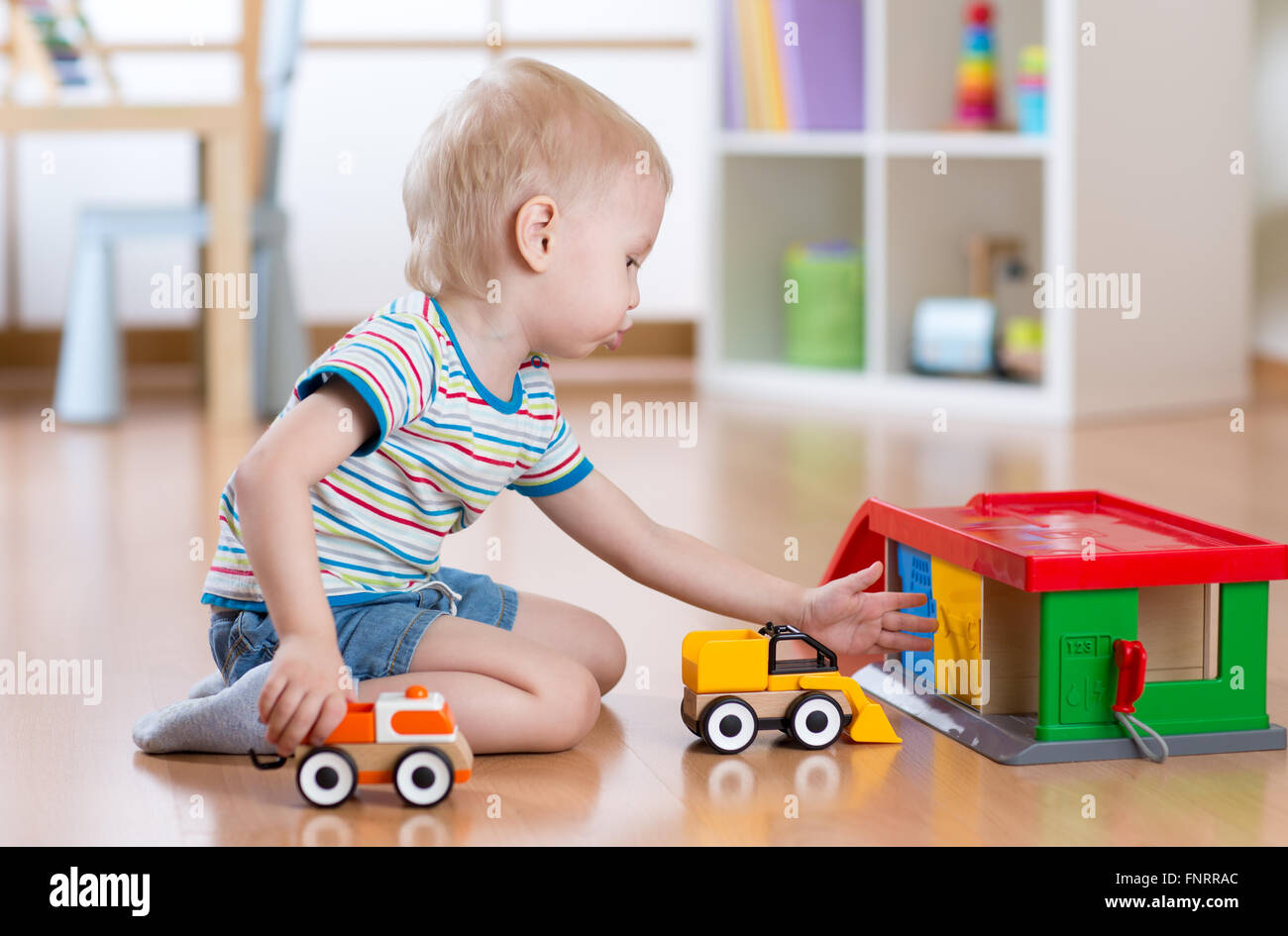 Little blond toddler kid boy plays with toy car Stock Photo