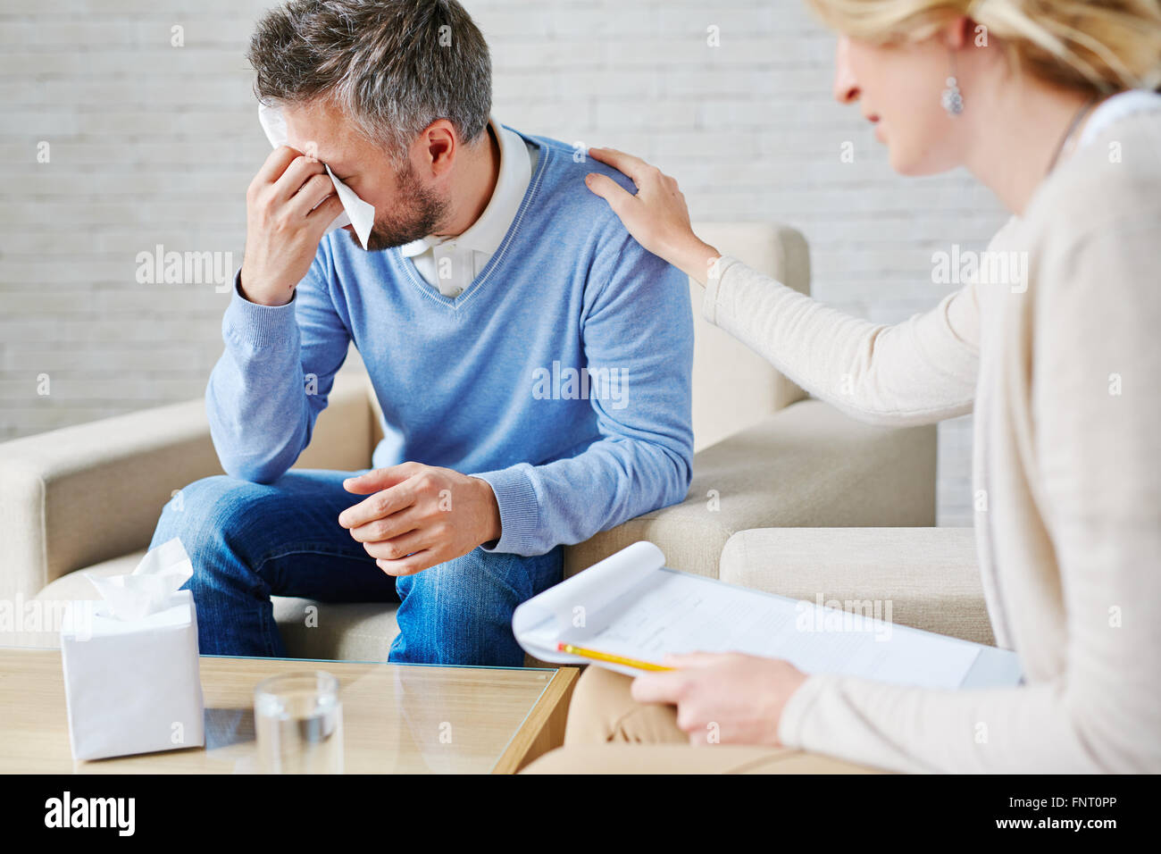 Depressed man crying while visiting his psychologist Stock Photo