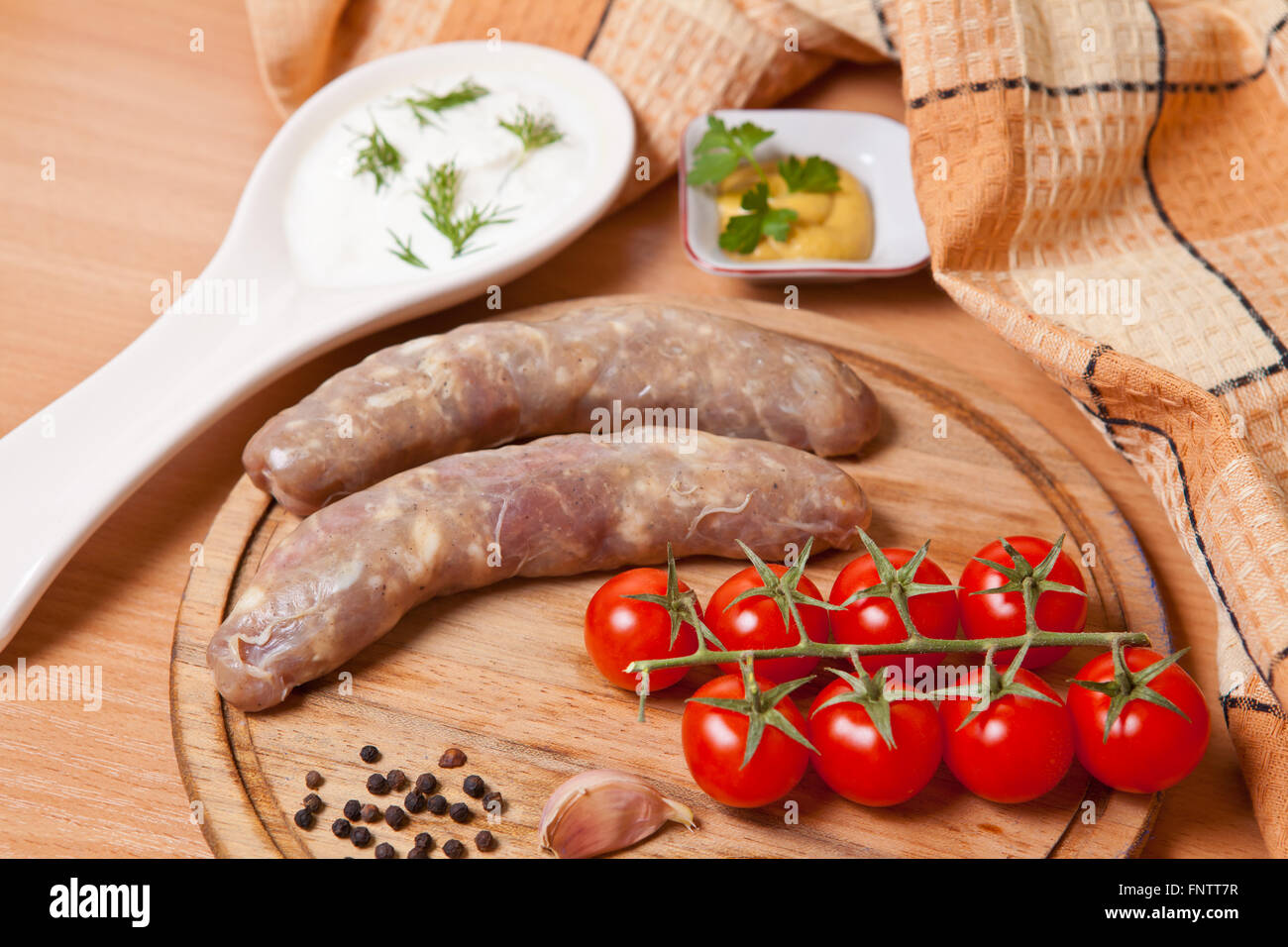 sausages in natural casing on a cutting board with cherry tomato Stock Photo