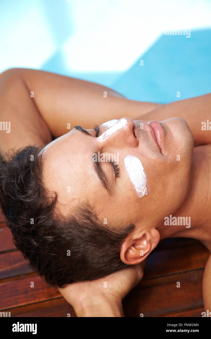 Relaxed man sunbathing with sunscreen on his nose and cheeks Stock
