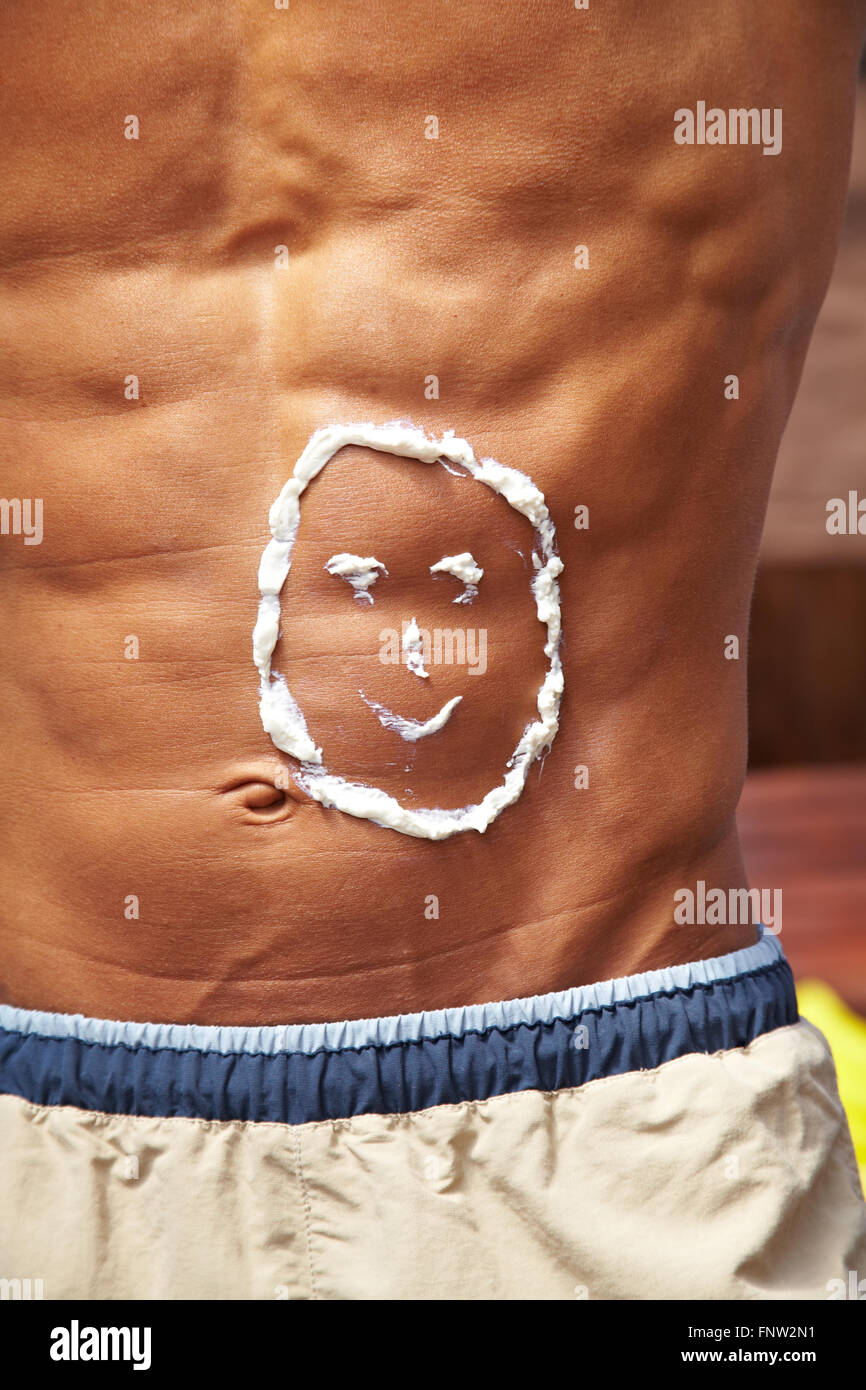 Sunscreen in smiley shape on male sixpack stomache Stock Photo