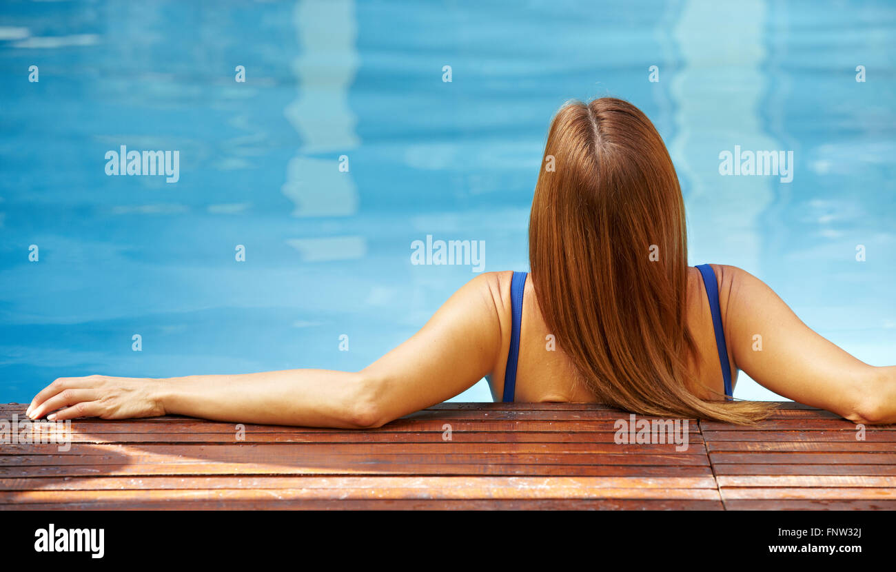 Back view of relaxed woman in swimming pool with blue water Stock Photo ...