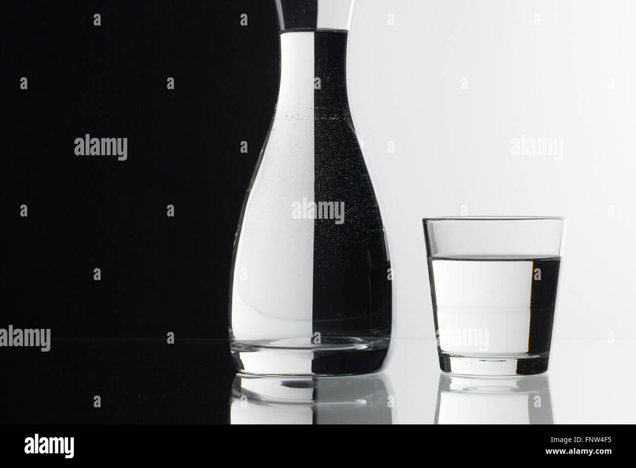 Glasses of water on the black and white background on the glass table Stock Photo