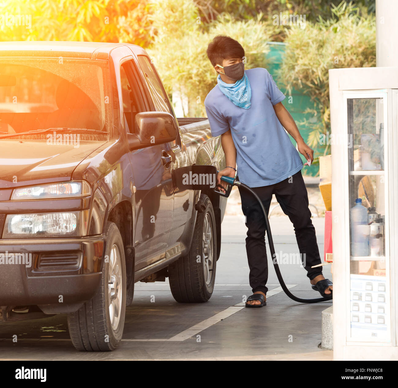 Asian man pumping gasoline fuel in car at gas station Stock Photo