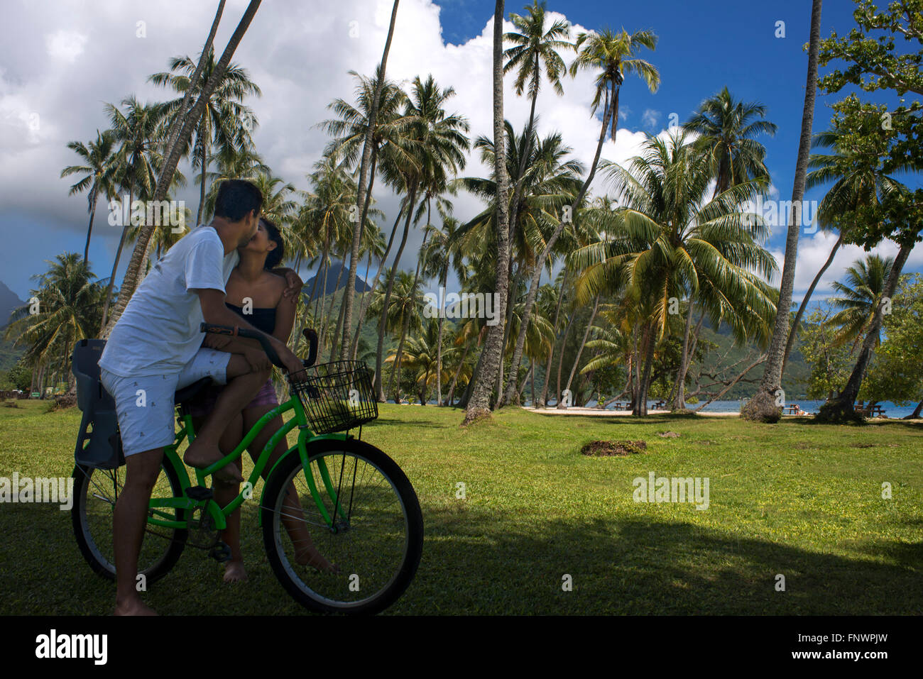 Local teens couple with a bicycle, kissing in Moorea, Cook's Capitan Bay, French Polynesia, Society Islands, South Pacific. Stock Photo