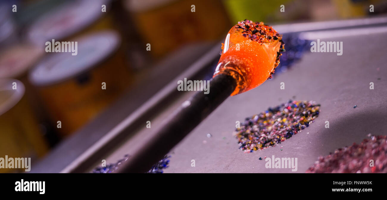 Glassblower adding color to hot glass Stock Photo