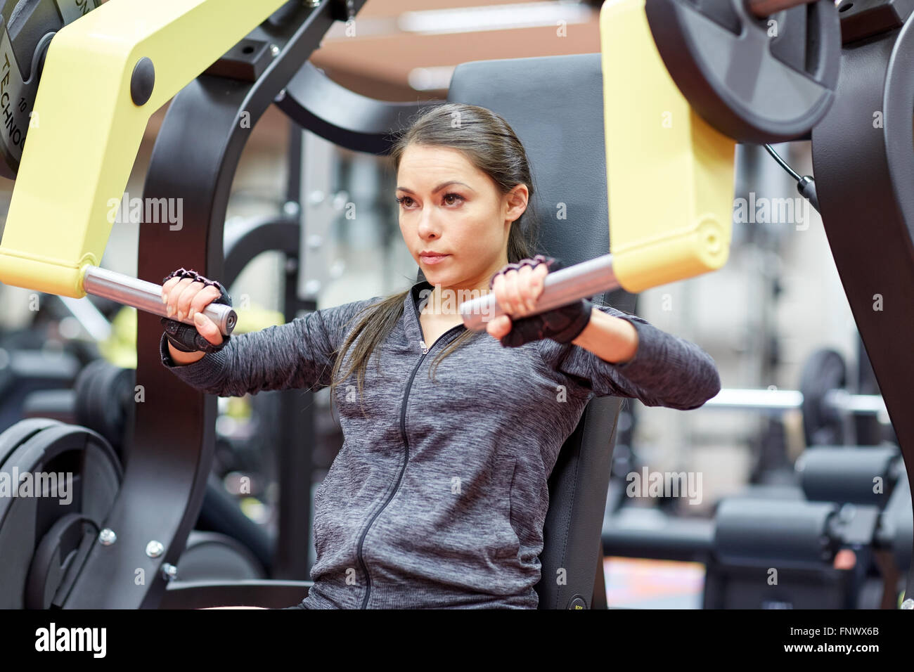 woman flexing muscles on chest press gym machine Stock Photo - Alamy