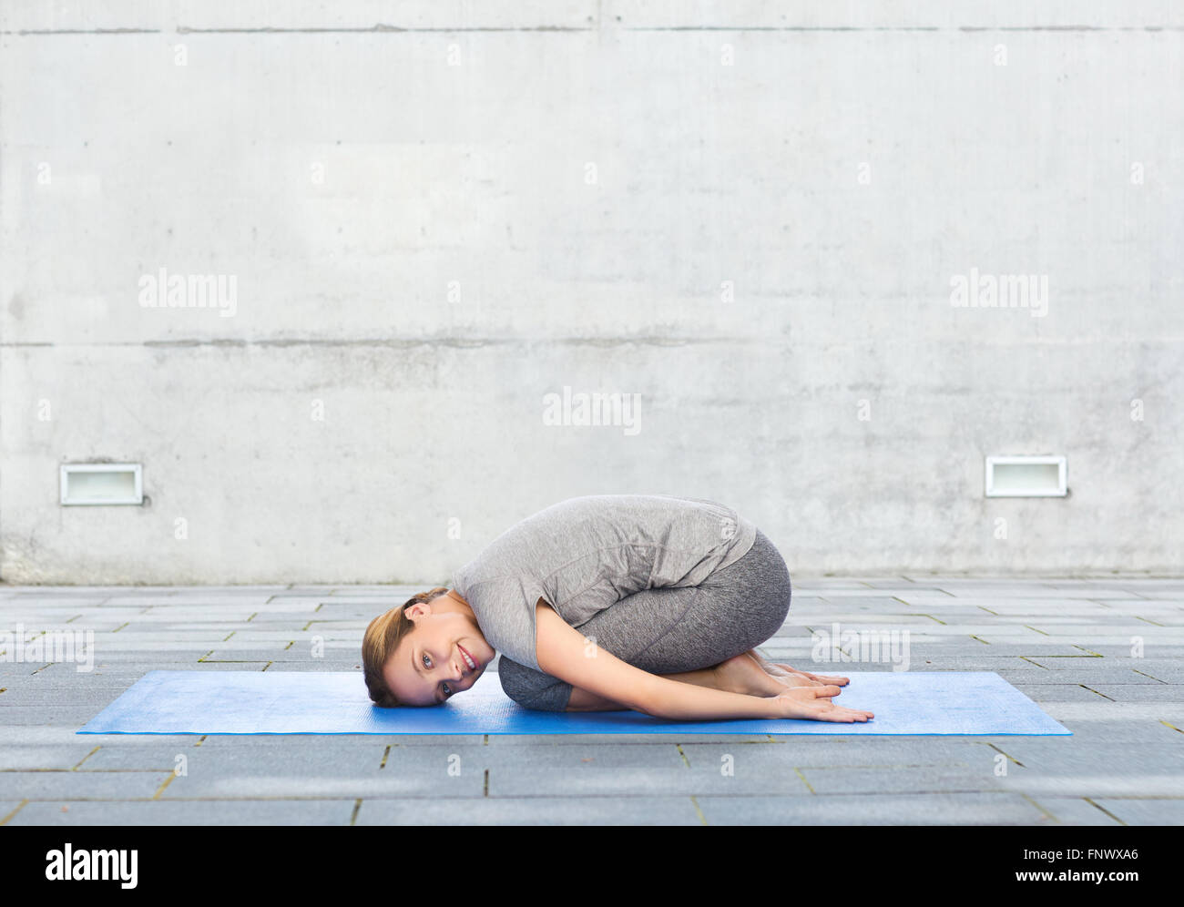 happy woman making yoga in child pose on mat Stock Photo - Alamy