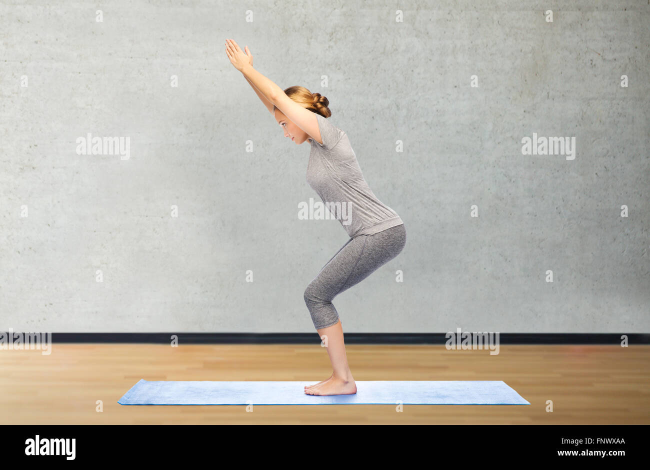 woman making yoga in chair pose on mat Stock Photo - Alamy