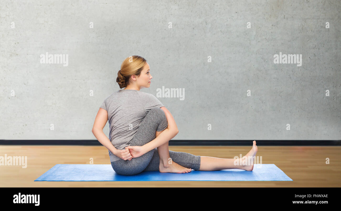 woman making yoga in twist pose on mat Stock Photo - Alamy