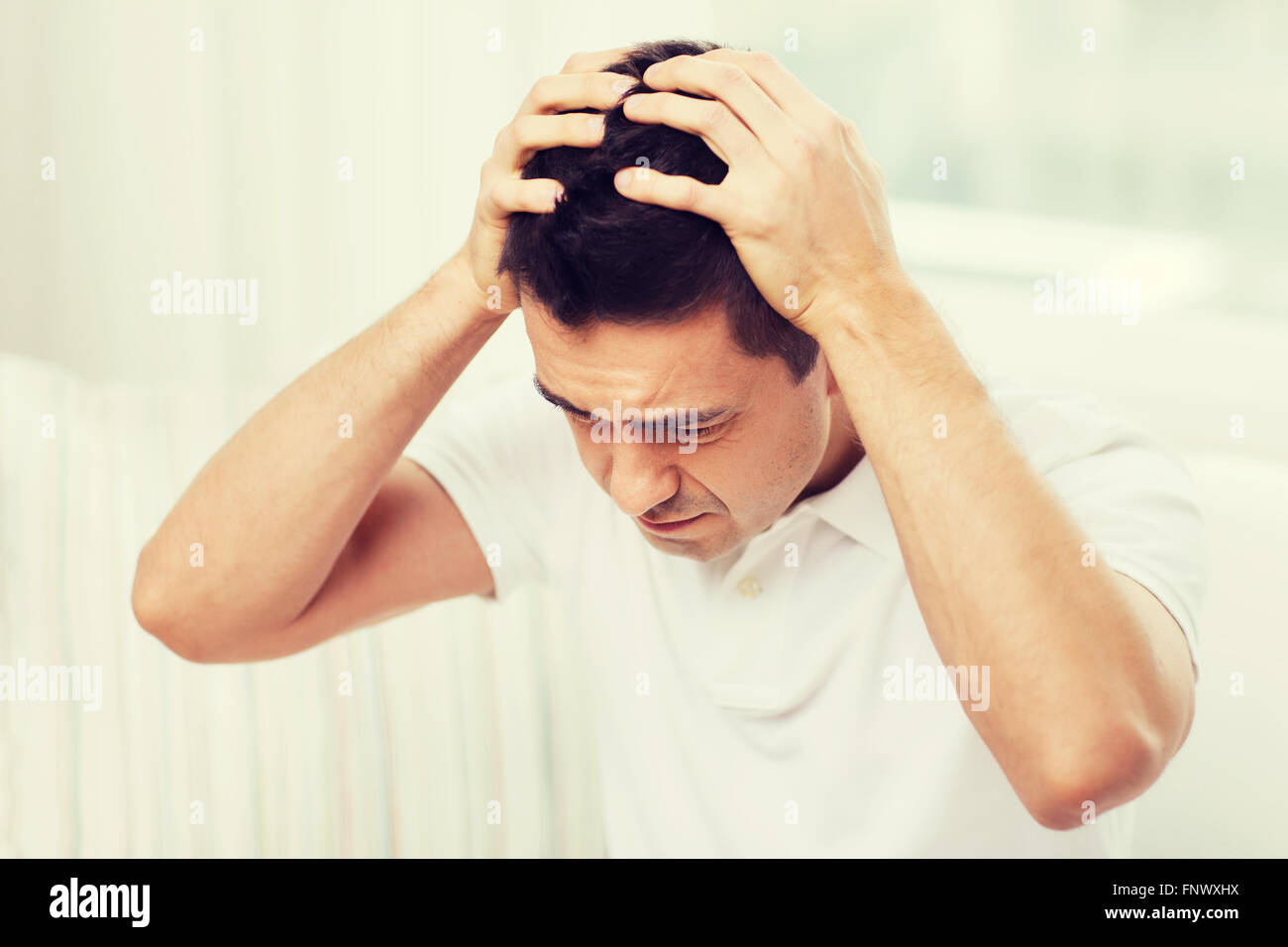 unhappy man suffering from head ache at home Stock Photo - Alamy