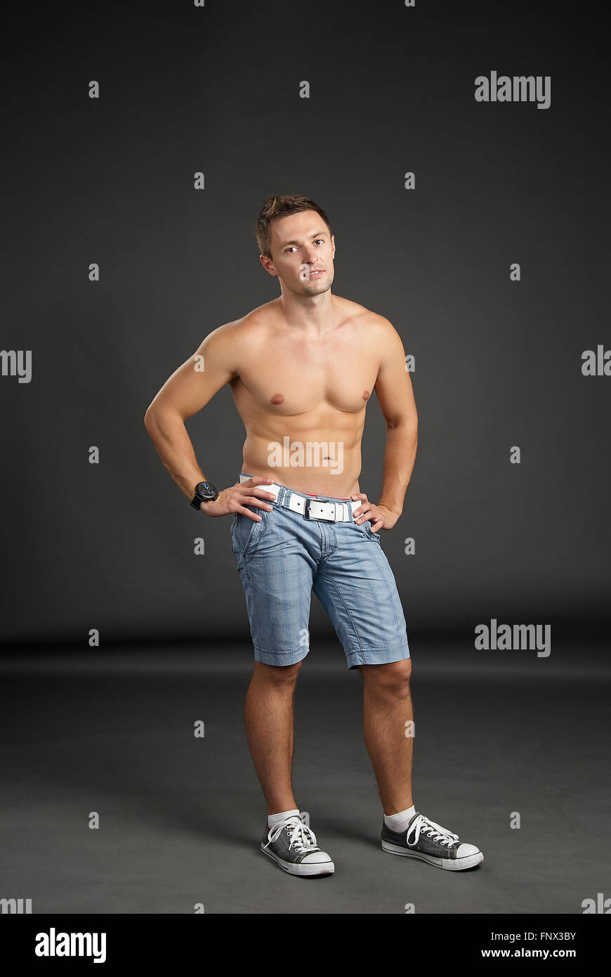 Portrait of young man standing against grey background Stock Photo - Alamy