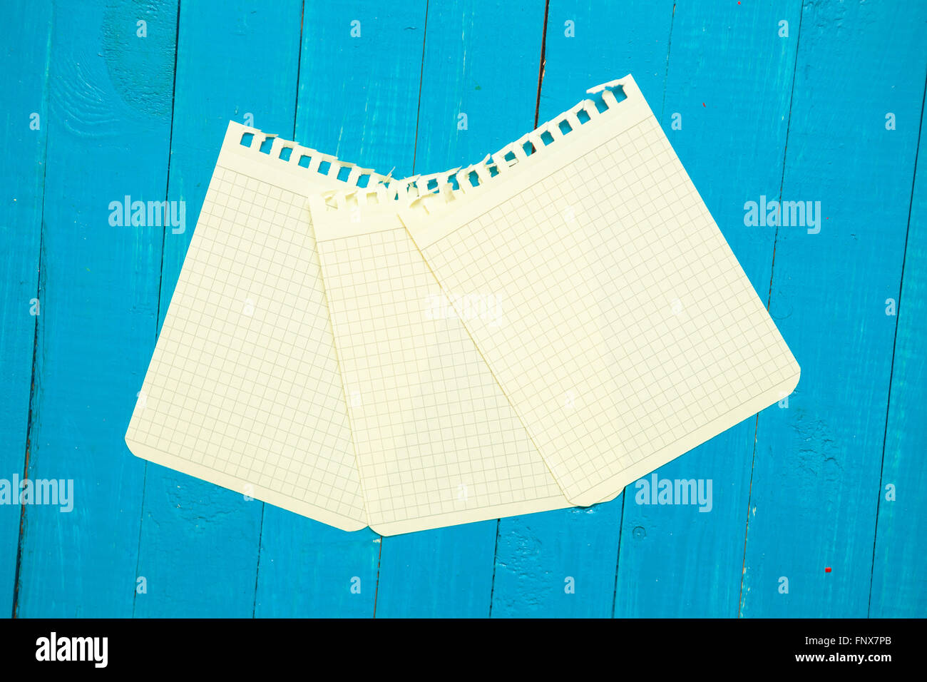 yellow sheet from a notebook on a blue wooden background Stock Photo