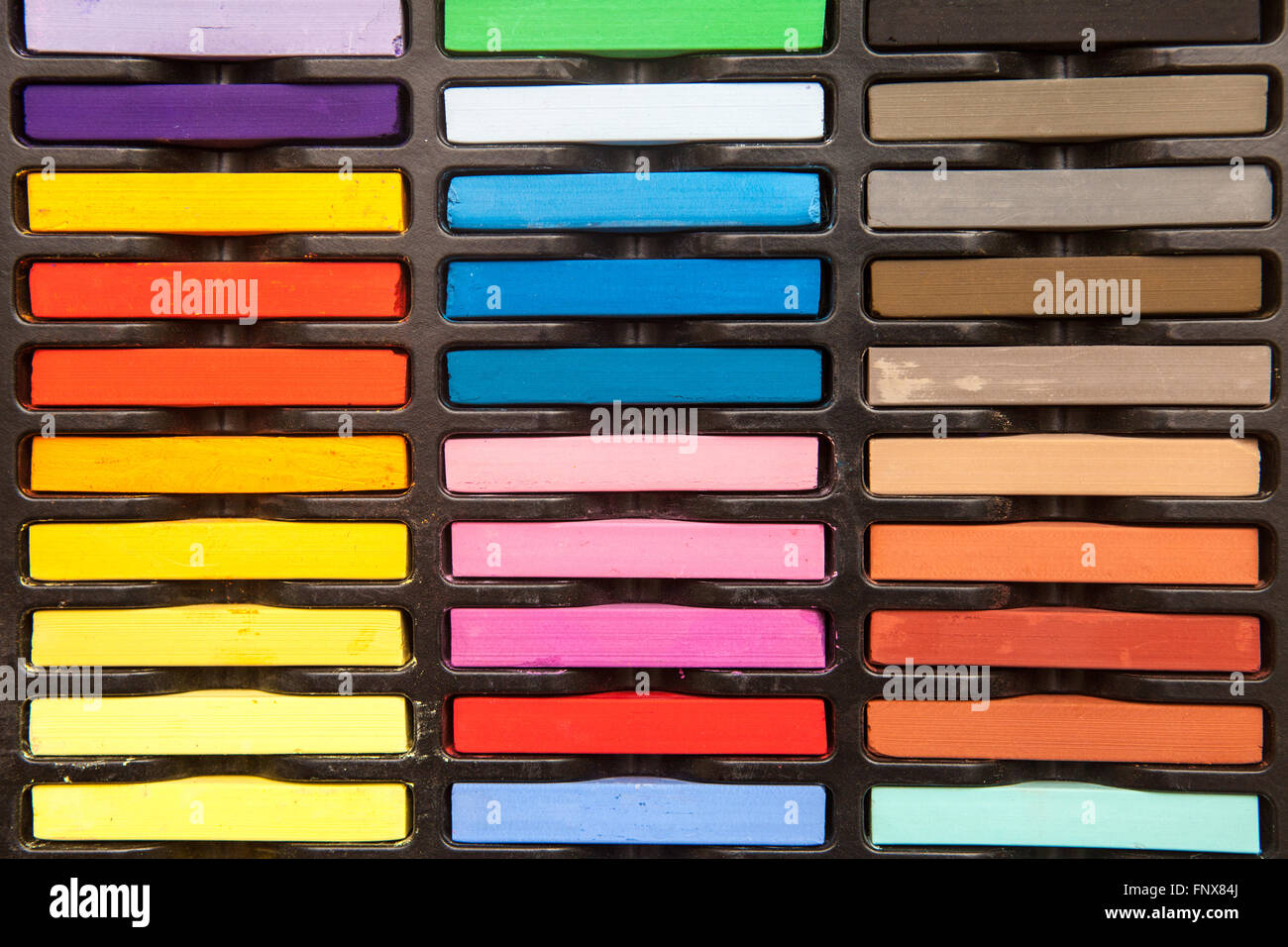colored pastels in a box on a wooden background Stock Photo