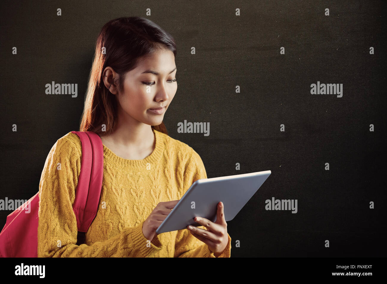 Composite image of focused asian female student using tablet Stock Photo