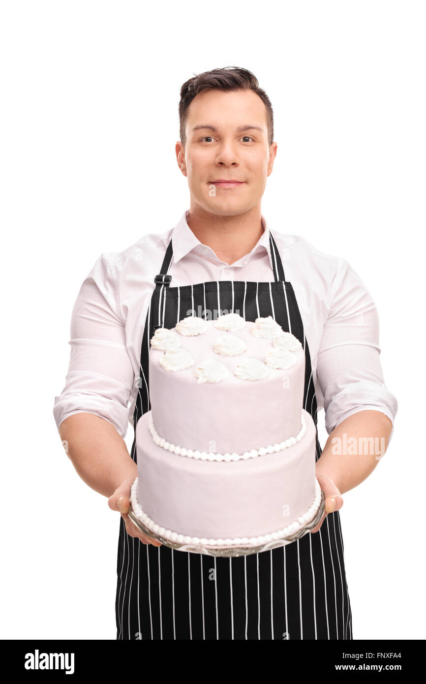 Vertical shot of a young pastry chef holding a large cake and looking at the camera isolated on white background Stock Photo