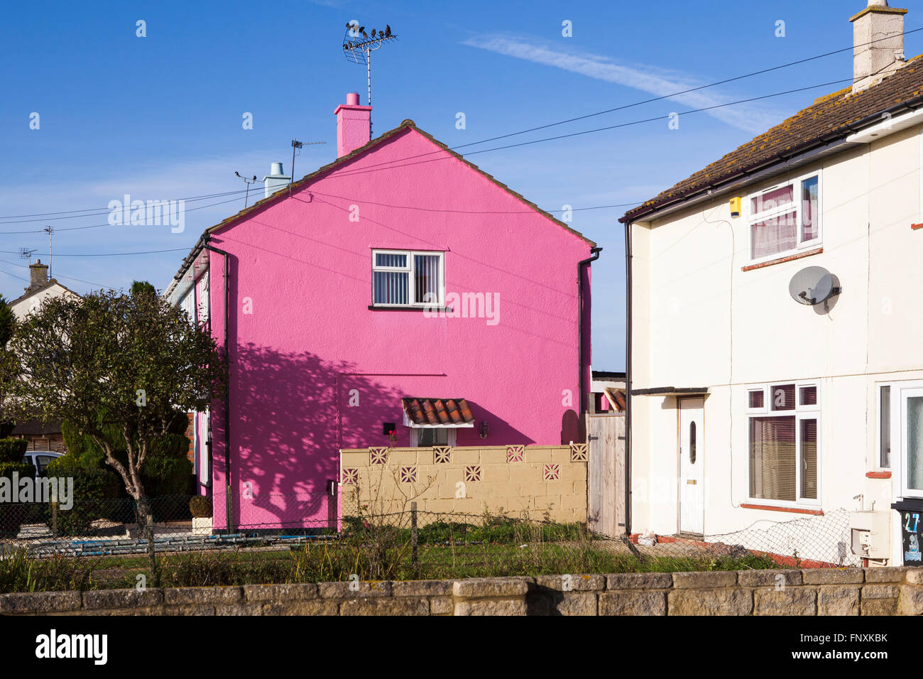 A small house painted pink and standing out from the crowd on a UK housing estate. Stock Photo