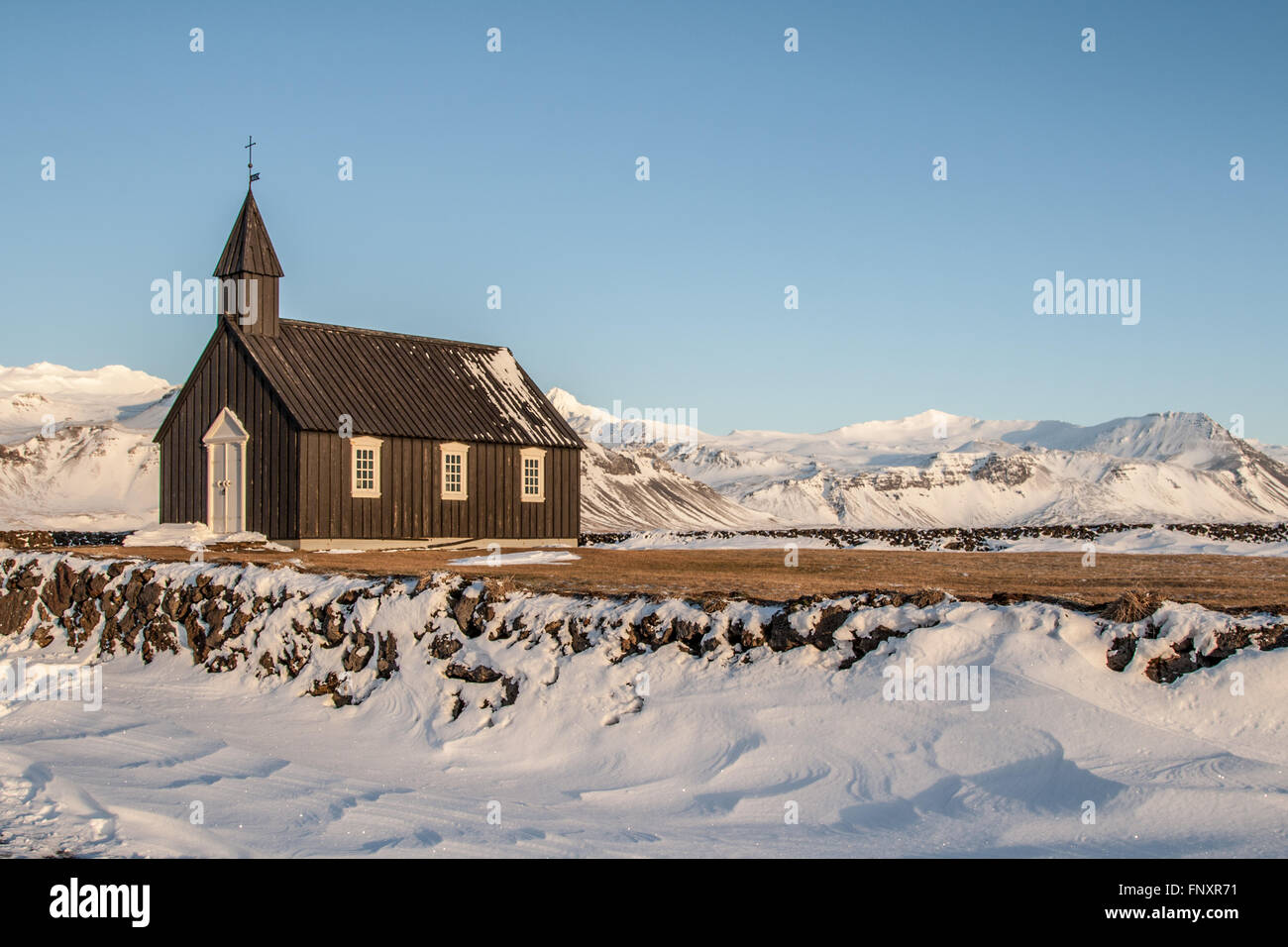 Wooden church at Budir surrounded by snow on a sunny winters day Stock Photo