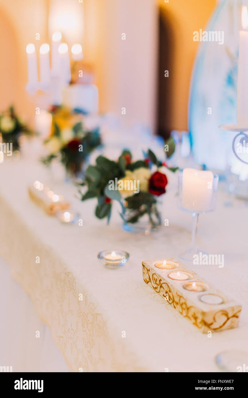 White wedding table decorated with flowers and candles ready for guests ...