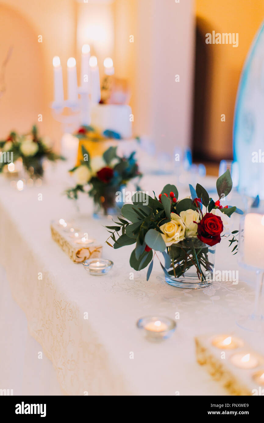 White wedding table decorated with flowers and candles ready for guests ...