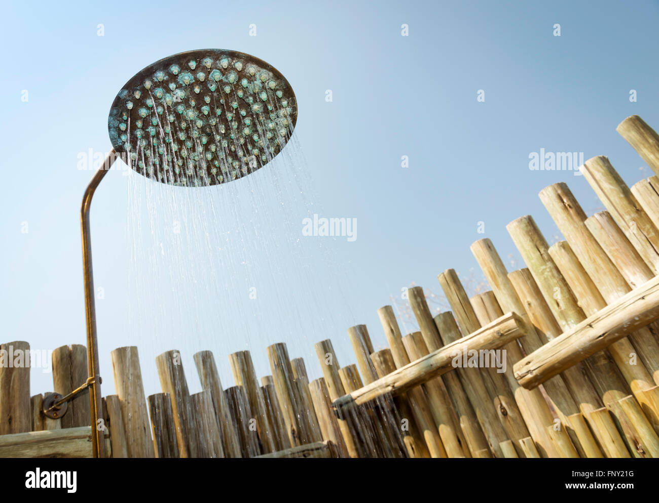 Outdoor shower with water coming out of the head and blue sky behind